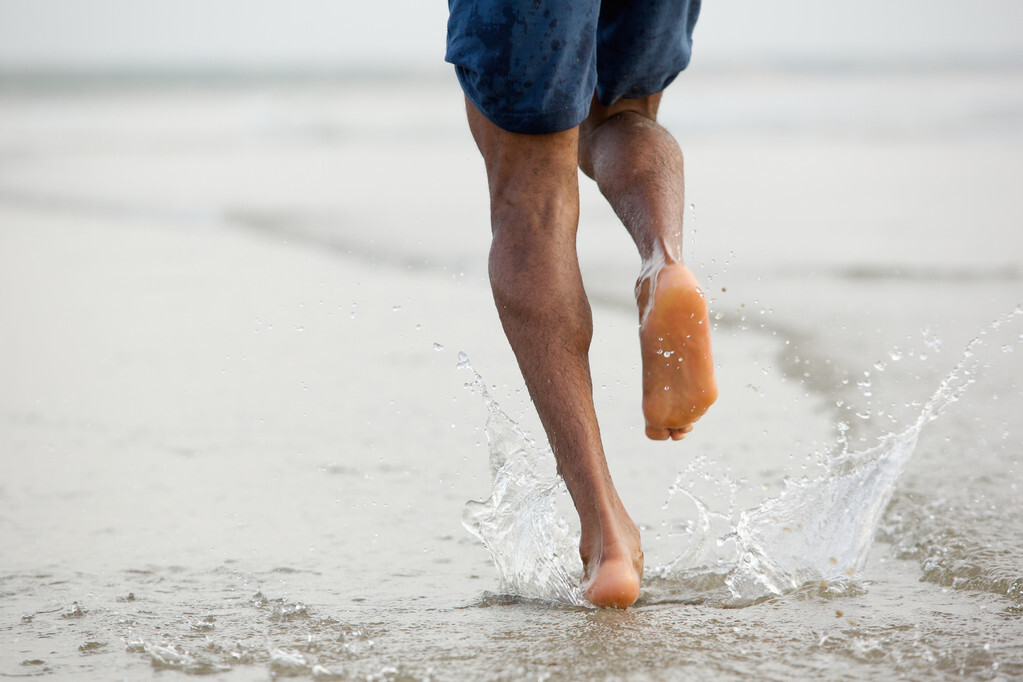 Man running barefoot in water
