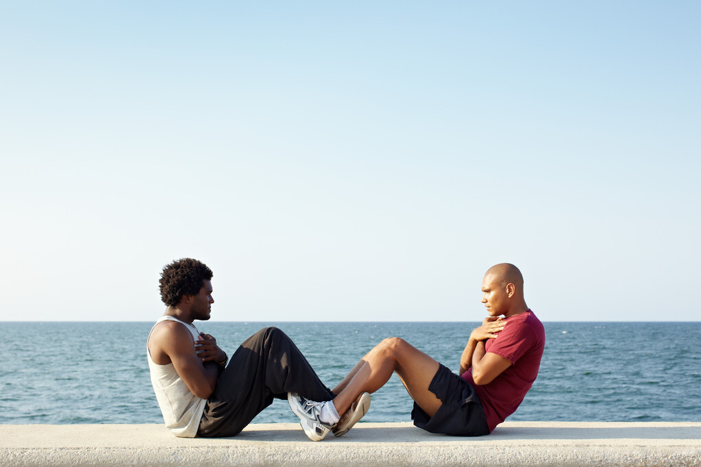 two men exercising abs near the sea